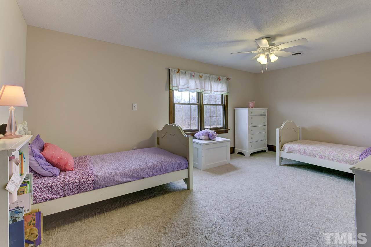 7850 James Austin Road Willow Spring, NC 27592 - Photo 16 of 25 a spacious bedroom with a bed and a chandelier