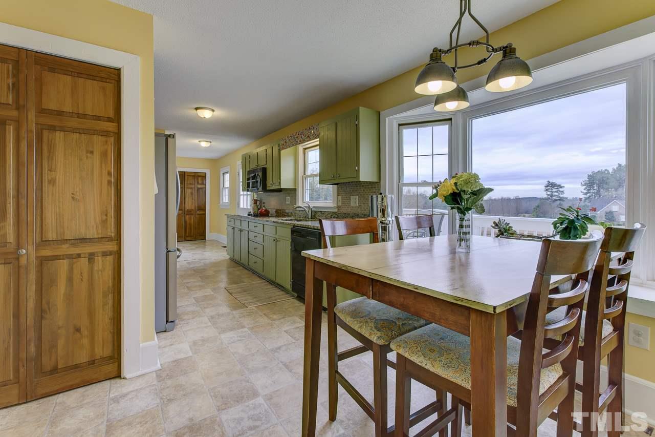 7850 James Austin Road Willow Spring, NC 27592 - Photo 6 of 25 a dining room with stainless steel appliances kitchen island granite countertop a table chairs and a refrigerator