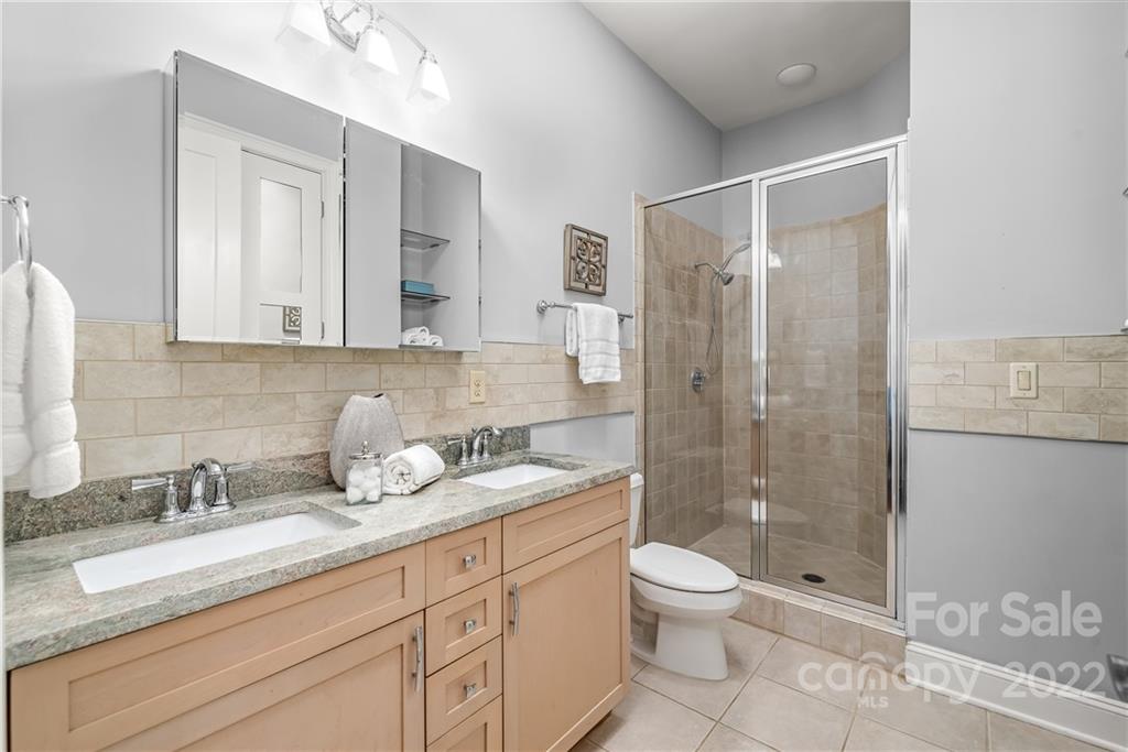 255 Queens Road, Unit 255 Charlotte, NC 28204 - Photo 19 of 32 a bathroom with a granite countertop sink toilet a large mirror a shower and vanity
