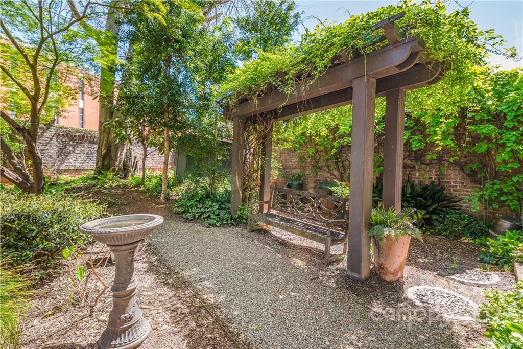 255 Queens Road, Unit 255 Charlotte, NC 28204 - Photo 29 of 32 a view of a patio with table and chairs potted plants and large tree