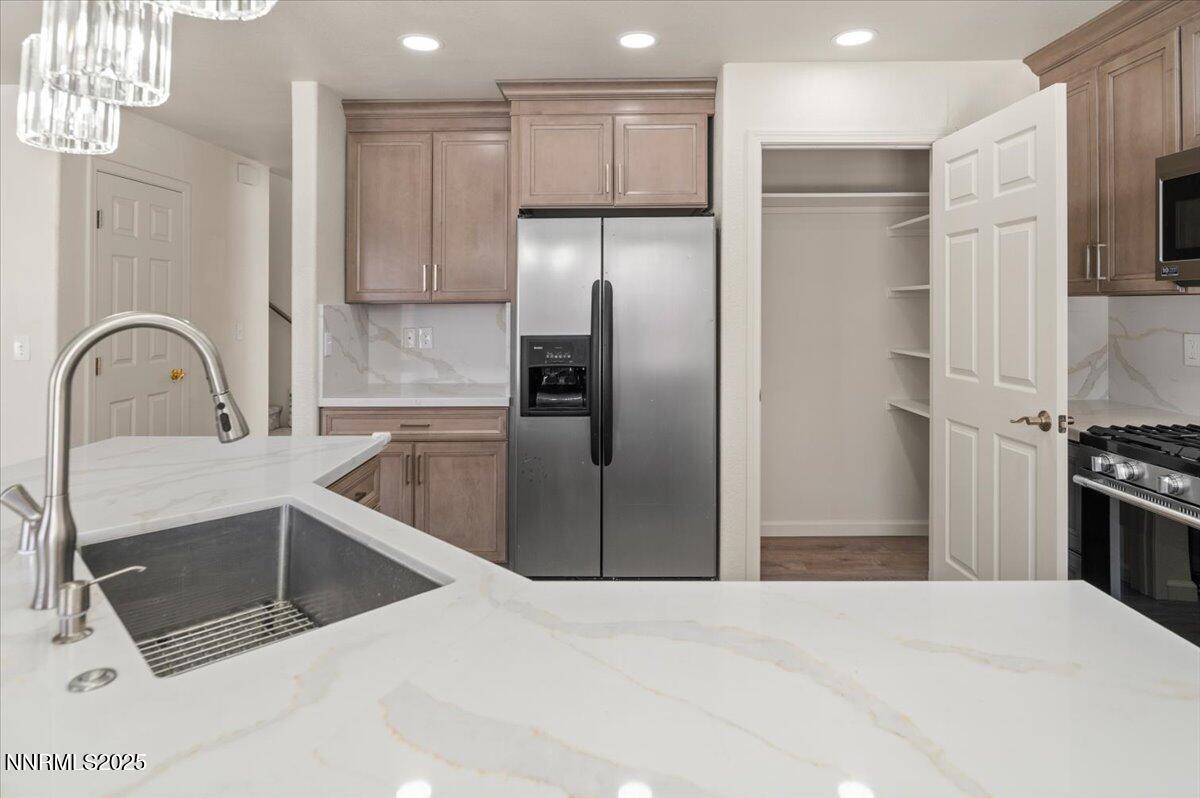 7753 Tulear Street Reno, NV 89506 - Photo 13 of 38 a kitchen with stainless steel appliances kitchen island granite countertop a refrigerator a sink a stove and a sink with wooden floor