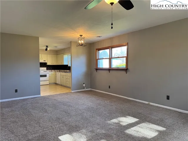 an empty room with chandelier fan and windows