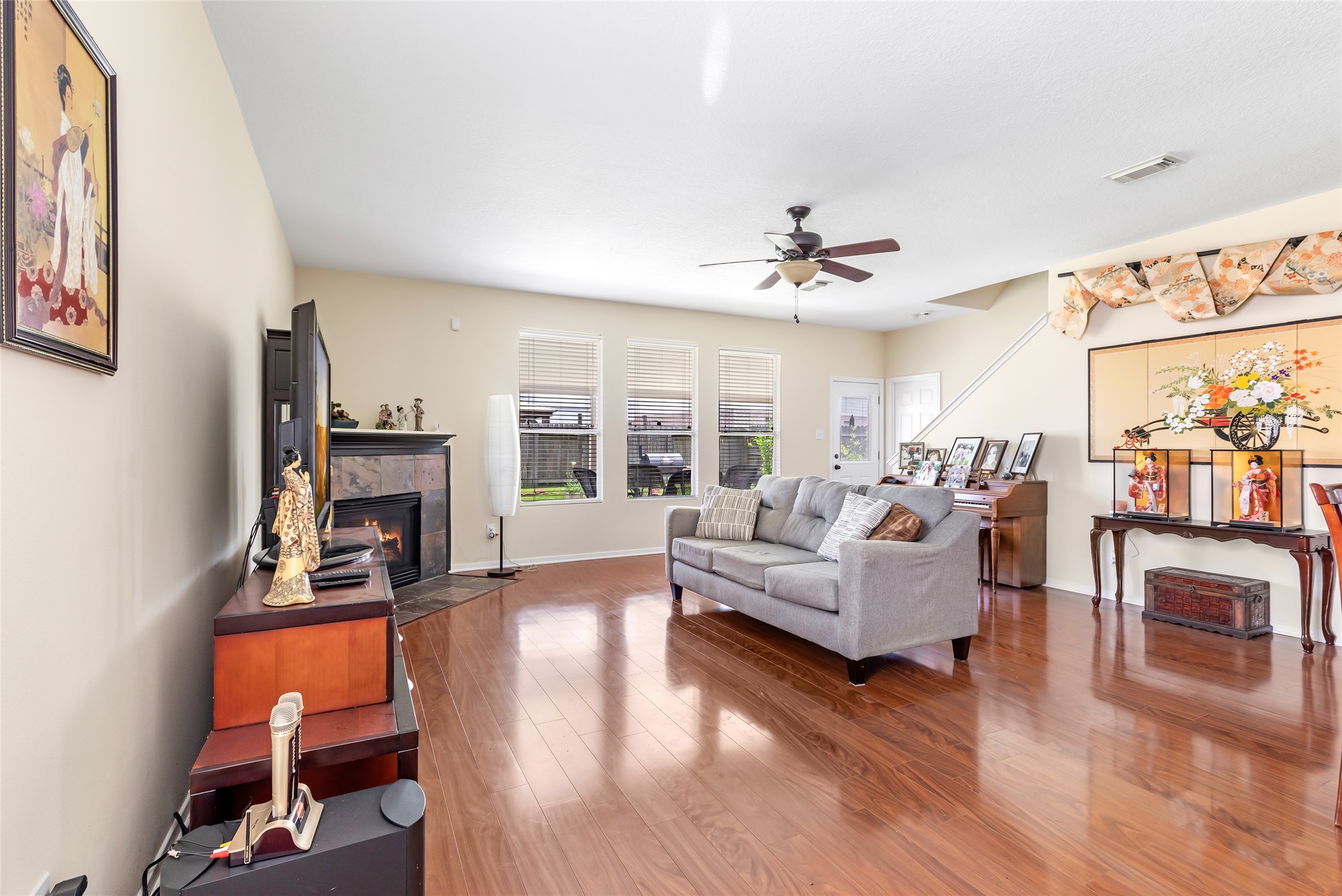 12122 Landsdown Ridge Way Humble, TX 77346 - Photo 8 of 34 This spacious living room features hardwood floors, a cozy fireplace, and abundant natural light from large windows. It includes a nice seating area, ceiling fan creating an inviting atmosphere perfect for relaxation and entertainment.