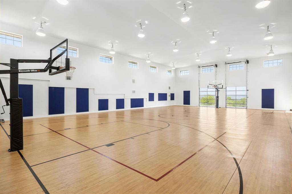 1180 McReynolds Road Sanger, TX 76266 - Photo 27 of 40 Indoor basketball court featuring wood-finish flooring, padded wall panels, multiple transom windows, and overhead task lighting