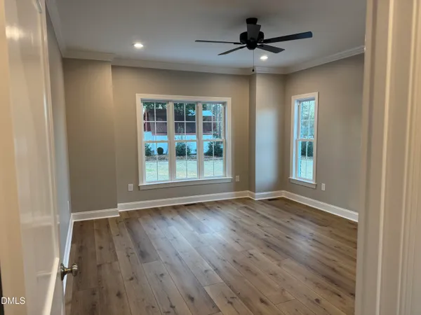 an empty room with wooden floor and windows