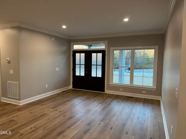 a view of an empty room with wooden floor and a window