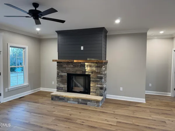 an empty room with wooden floor a fireplace and windows