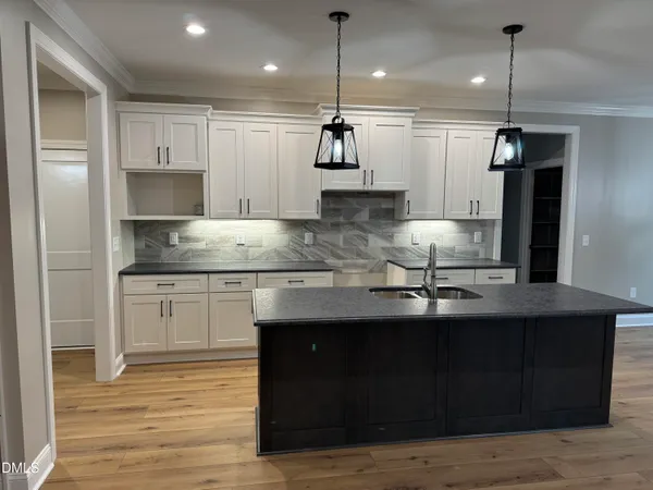 a kitchen with stainless steel appliances granite countertop a sink a stove a refrigerator and island with wooden floor