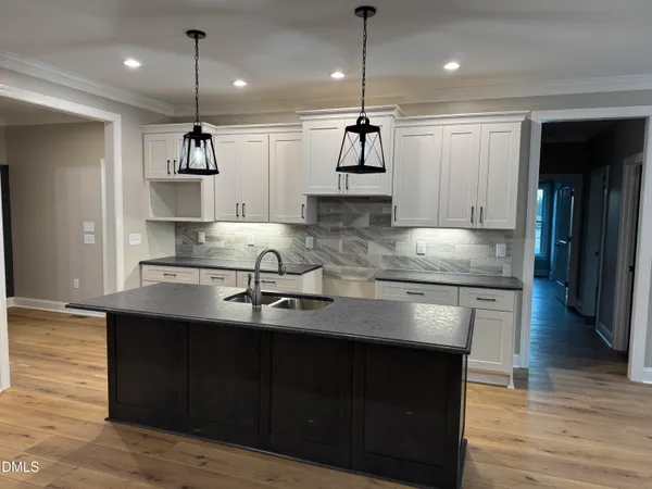 a kitchen with kitchen island granite countertop a sink appliances and wooden floor