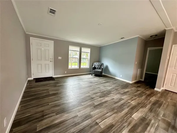 an empty room with wooden floor and windows