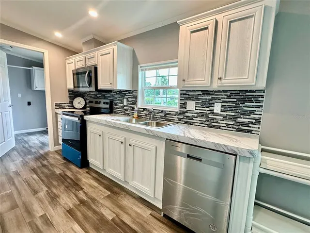 a kitchen with kitchen island a sink stainless steel appliances and wooden floor