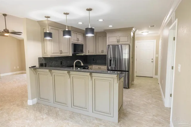 a kitchen with kitchen island granite countertop a refrigerator a sink and white cabinets