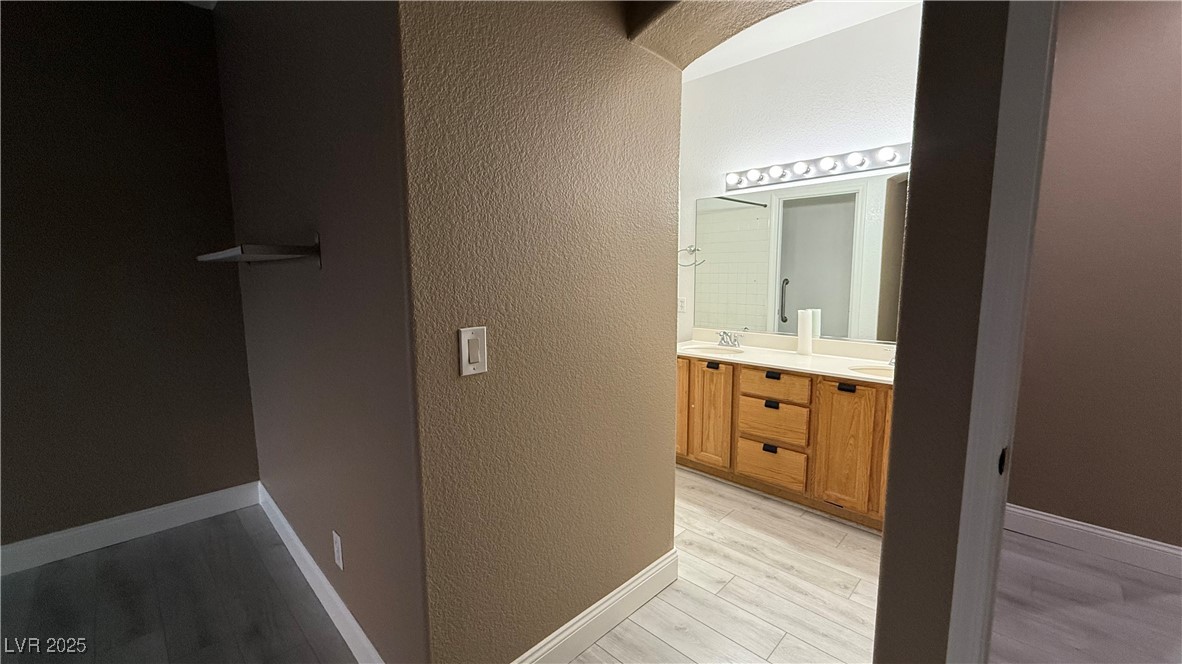 7062 Russell Ranch Avenue Las Vegas, NV 89113 - Photo 26 of 32 Bathroom with a textured wall, wood finished floors, a sink, double vanity, and baseboards
