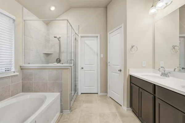 a bathroom with a bathtub shower sink vanity and mirror