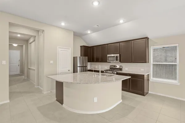 a large kitchen with stainless steel appliances granite countertop a stove a sink a refrigerator and a cabinets