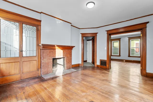 a view of an empty room with window and wooden floor