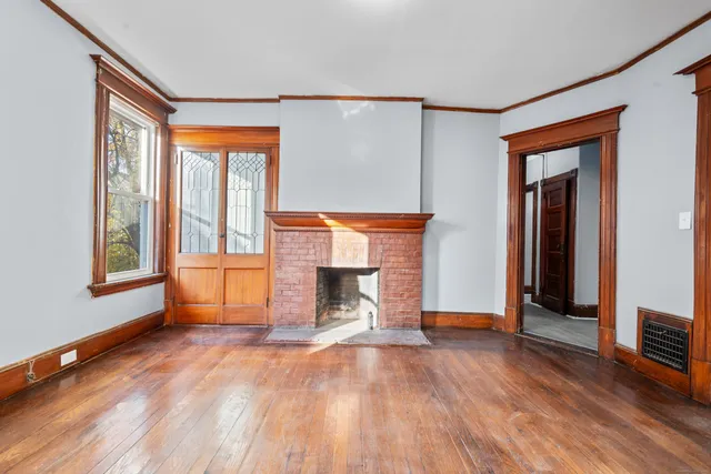 a view of empty room with a fireplace and wooden floor