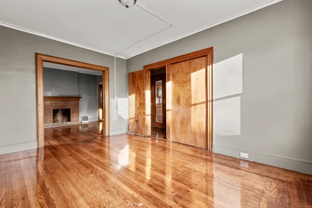 a view of empty room with wooden floor and fan