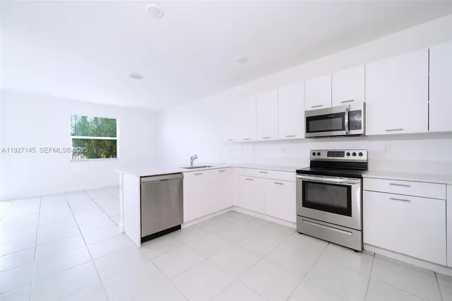 a kitchen with granite countertop white cabinets and stainless steel appliances