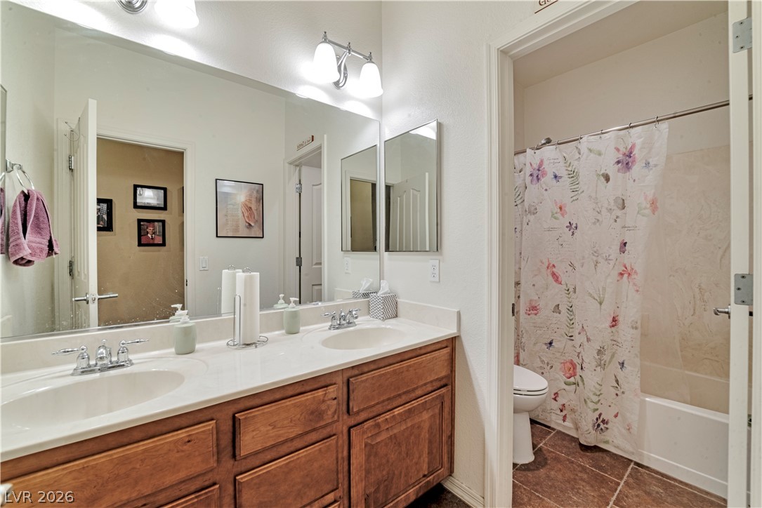 5915 Karnes Ranch Avenue Las Vegas, NV 89131 - Photo 12 of 28 Full bathroom with double vanity, shower / bath combo, and dark tile patterned floors