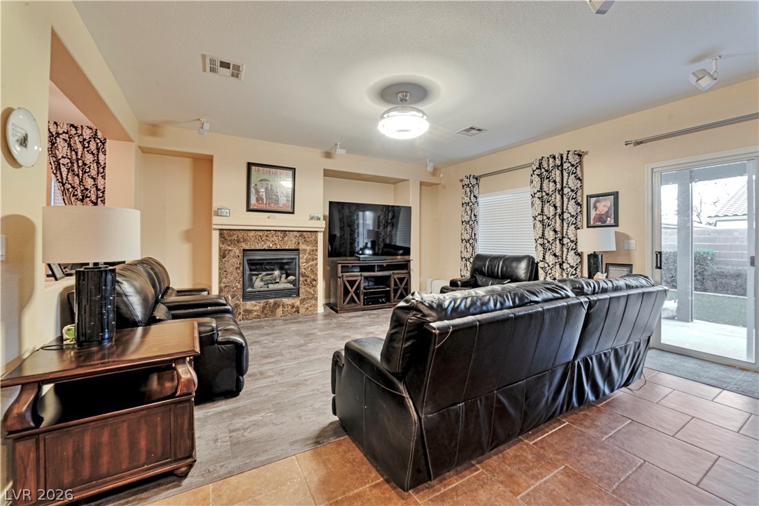 5915 Karnes Ranch Avenue Las Vegas, NV 89131 - Photo 28 of 28 Living room featuring a tiled fireplace and light tile patterned floors