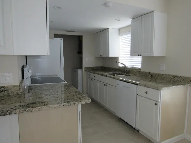 a kitchen with granite countertop a sink a stove and cabinets