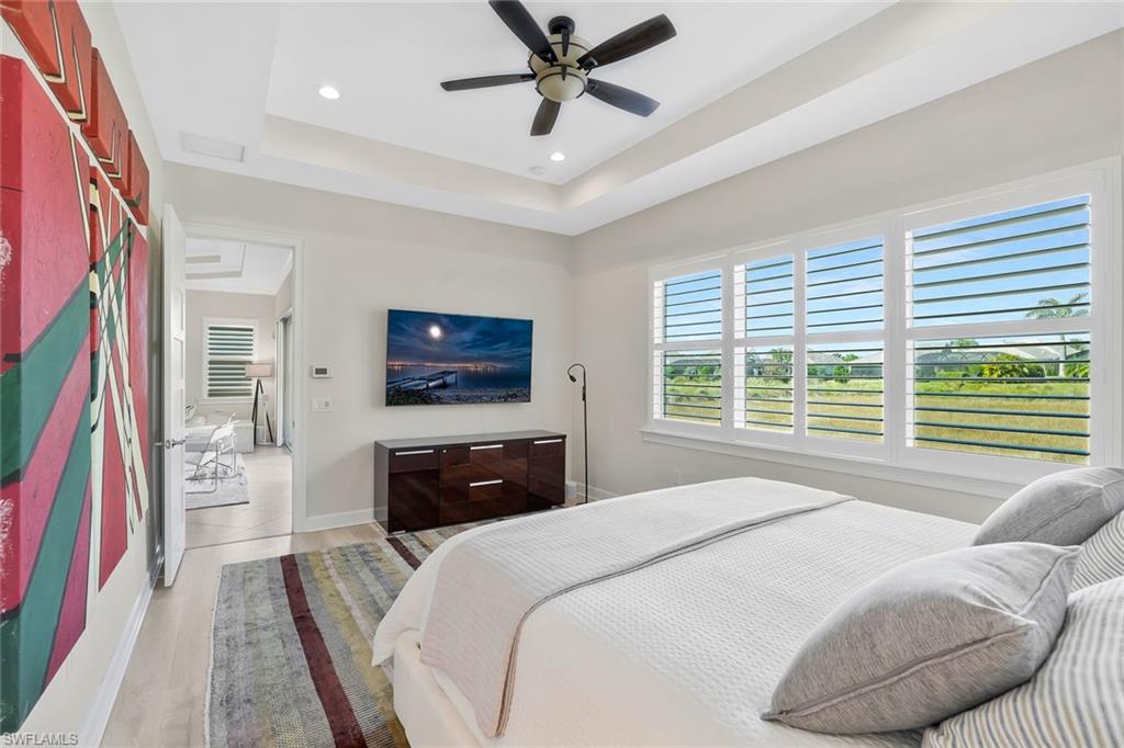 5167 Andros Drive Naples, FL 34113 - Photo 13 of 32 a bedroom with a bed a dresser and a flat screen tv