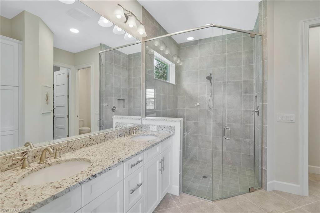 5167 Andros Drive Naples, FL 34113 - Photo 14 of 32 a bathroom with a granite countertop sink shower and a mirror