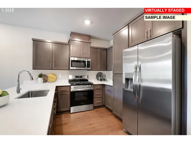 a kitchen with stainless steel appliances granite countertop a refrigerator a stove and a sink