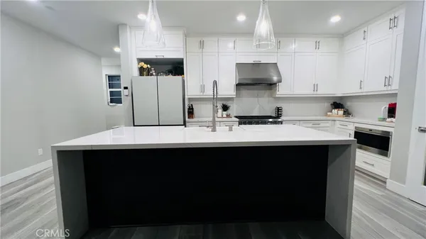 a kitchen with stainless steel appliances a sink a stove a refrigerator and cabinets