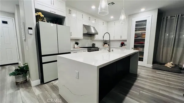 a kitchen with stainless steel appliances kitchen island granite countertop a refrigerator a sink a stove and oven with wooden floor