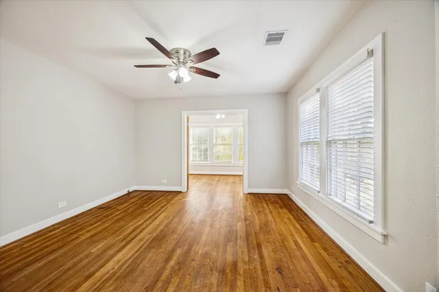 a view of empty room with wooden floor and fan