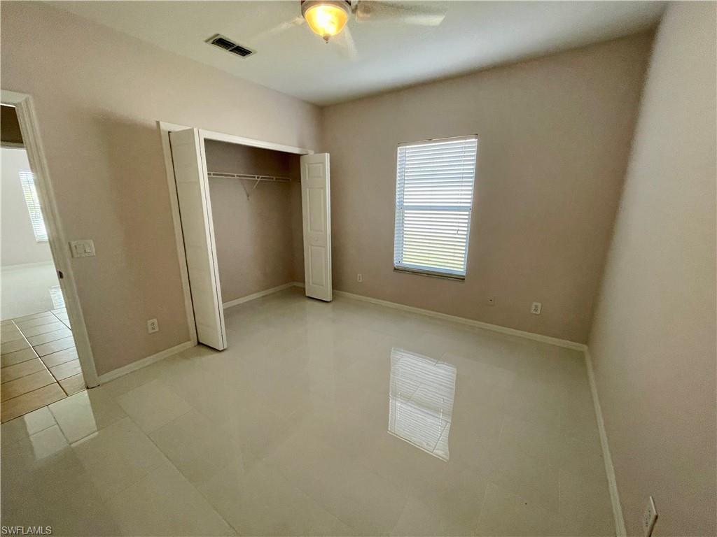 2895 Orange Grove Trail Naples, FL 34120 - Photo 18 of 33 an empty room with a windows and chandelier fan