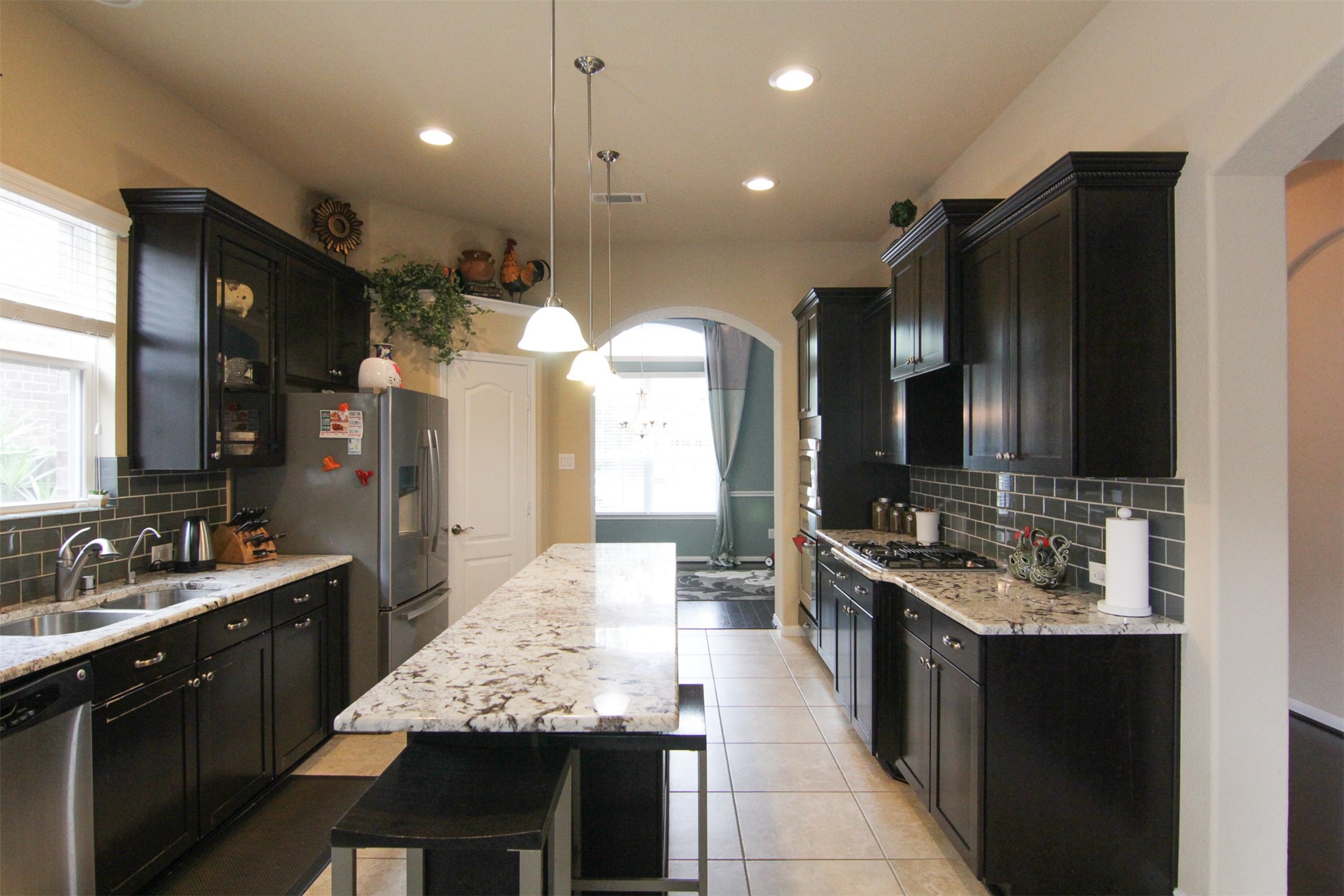 1423 Ralston Branch Way Sugar Land, TX 77479 - Photo 12 of 43 gorgeous lighter-colored, high-end granite countertops; smooth backsplash tiles; triple pendant lights over long island -- perfect for a buffet spread to entertain