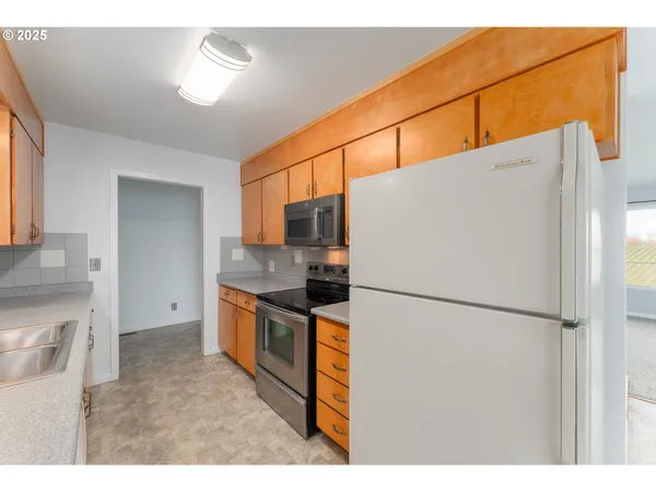 a kitchen with stainless steel appliances granite countertop a refrigerator a stove a sink and a refrigerator