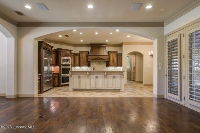 a view of empty room with chandelier fan and refrigerator