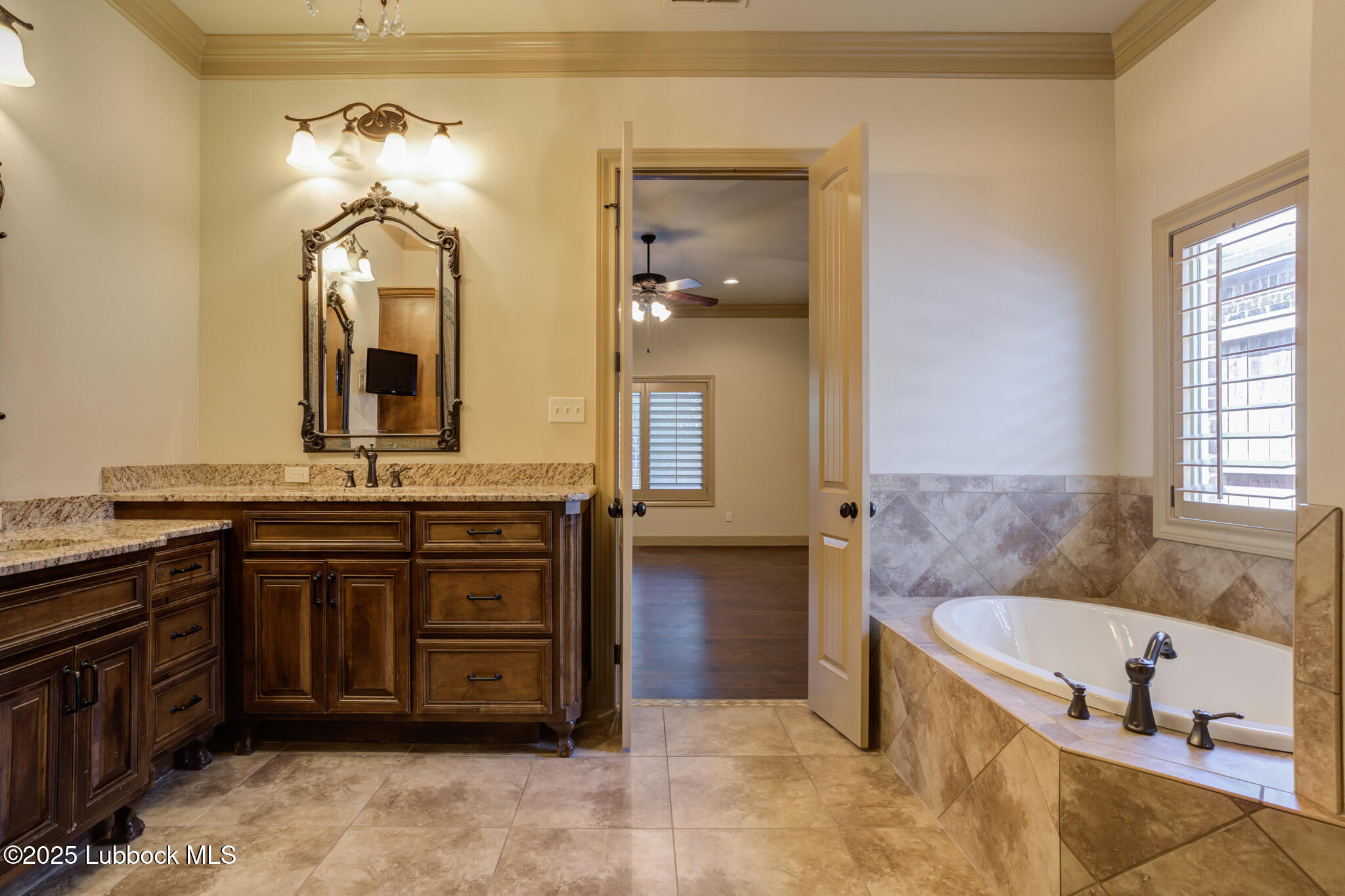 6103 89th Street Lubbock, TX 79424 - Photo 66 of 73 a bathroom with a granite countertop tub double vanity sink and a mirror