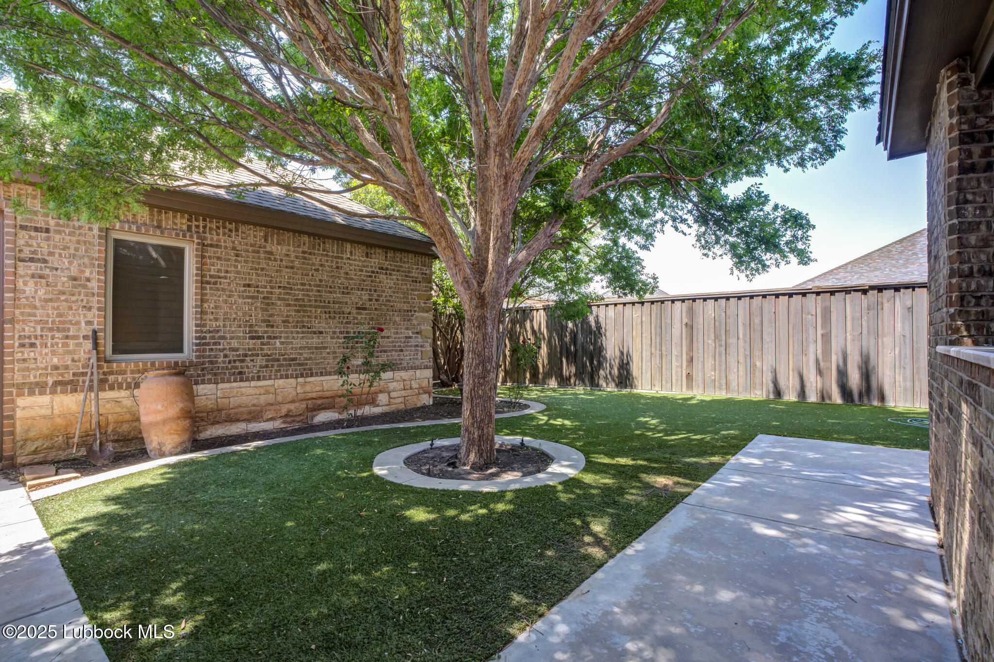 6103 89th Street Lubbock, TX 79424 - Photo 70 of 73 a view of a backyard with table and chairs potted plants and a large tree