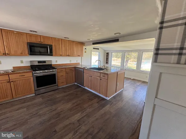 a kitchen with stainless steel appliances kitchen island granite countertop wooden floors and white cabinets