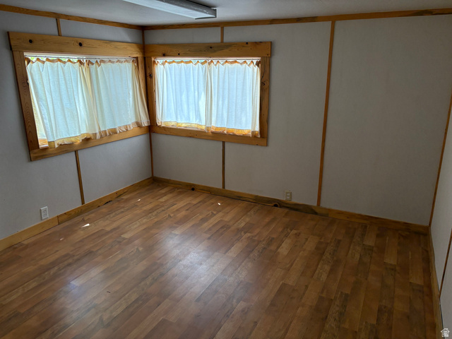 700 West Gravel Road North Kanab, UT 84741 - Photo 42 of 63 Wood-finish flooring, two large windows with natural wood trim, white walls, and a ceiling-mounted fluorescent light fixture
