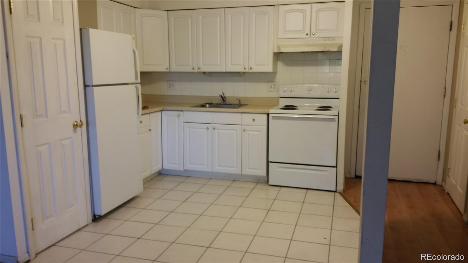 1304 South Parker Road, Unit 240 Denver, CO 80231 - Photo 6 of 19 a kitchen with white cabinets and white appliances