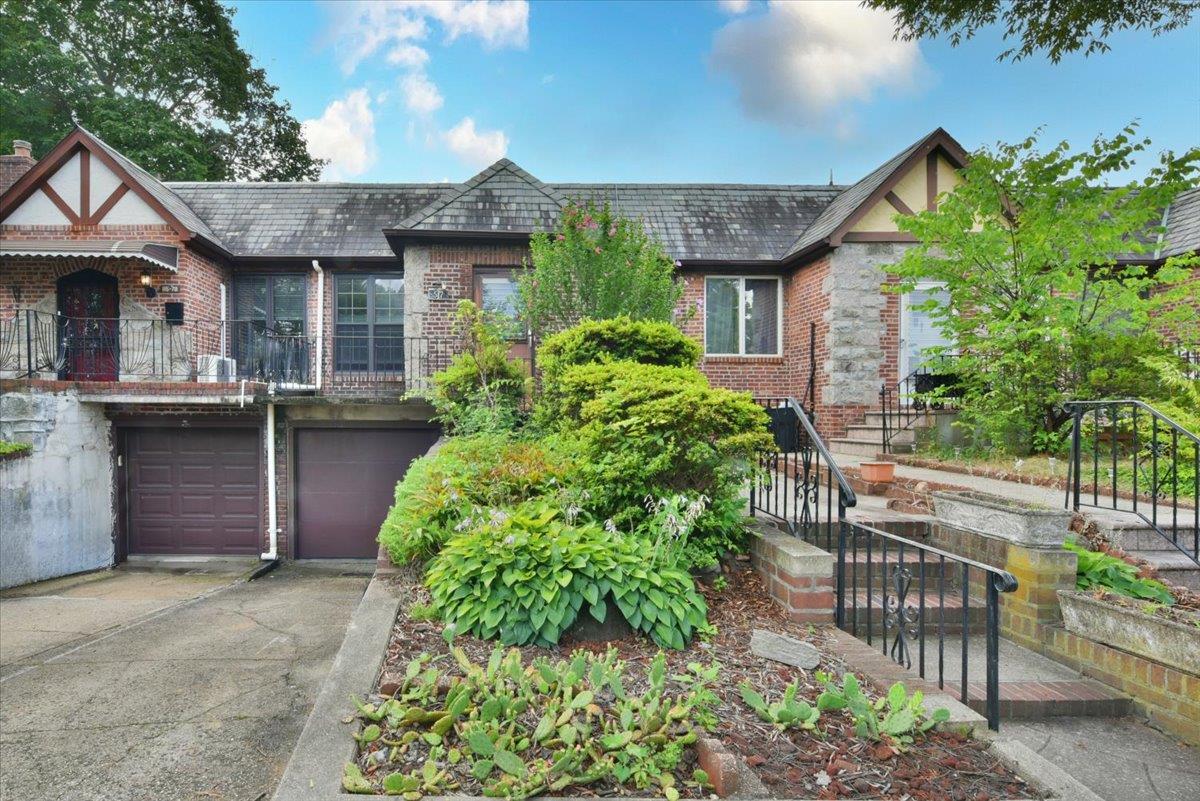 Tudor-style house featuring brick siding, concrete driveway, a garage, and a balcony