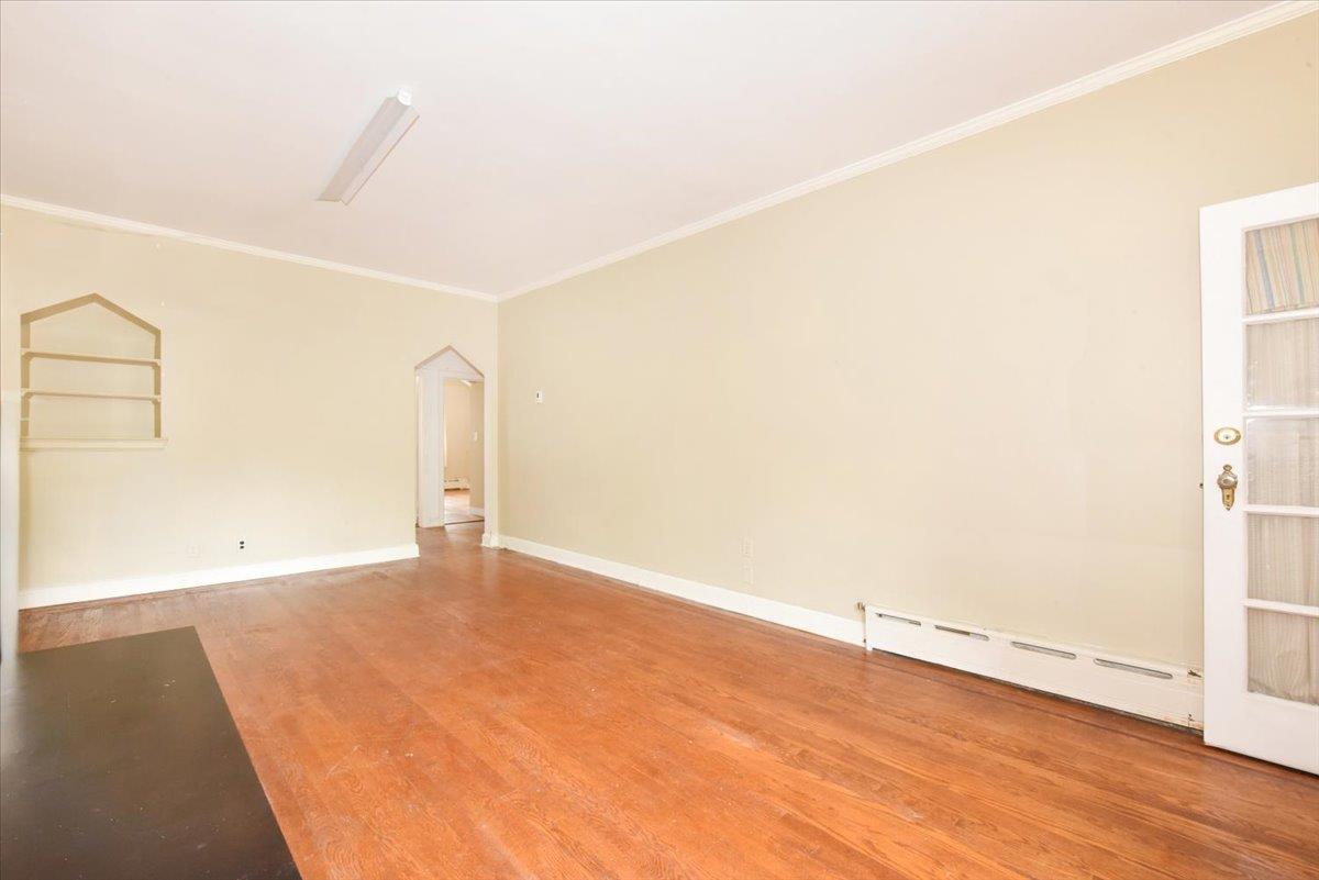 85-76 66th Road Queens, NY 11374 - Photo 4 of 20 Spare room featuring crown molding, a baseboard radiator, and wood finished floors