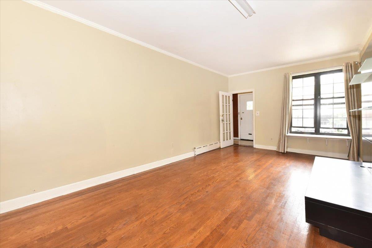 85-76 66th Road Queens, NY 11374 - Photo 5 of 20 Empty room with ornamental molding, wood finished floors, and a baseboard heating unit