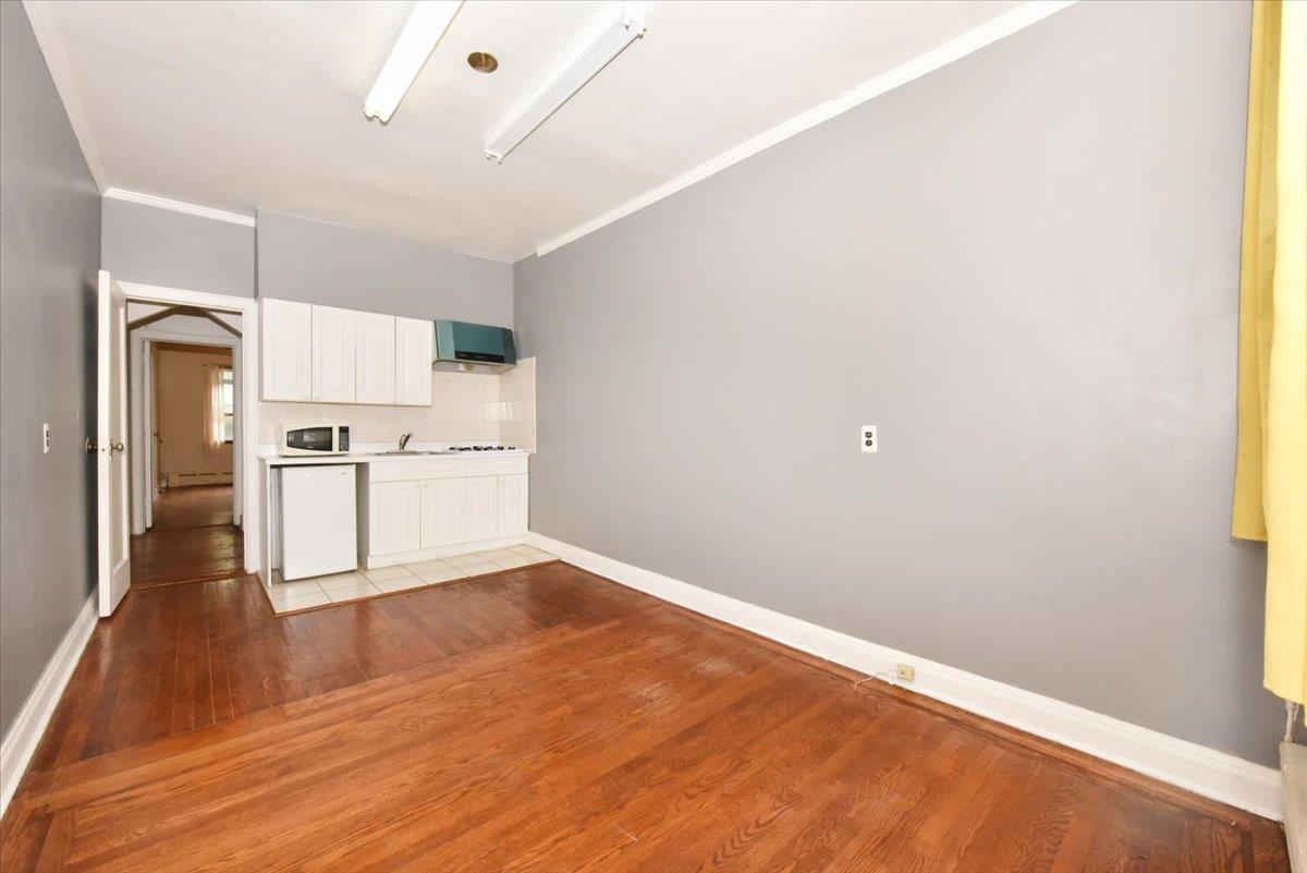 85-76 66th Road Queens, NY 11374 - Photo 8 of 20 Kitchen featuring light wood-type flooring, light countertops, ornamental molding, range hood, and white cabinets