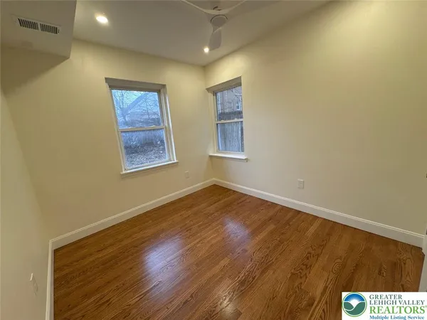 a view of an empty room with wooden floor and a window