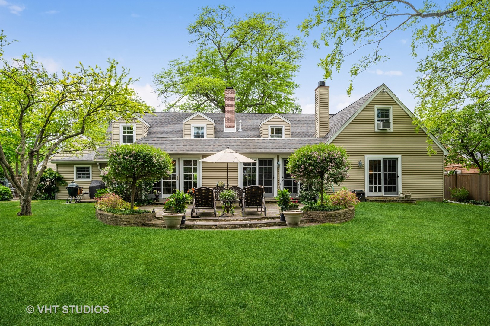 a front view of a house with garden and trees