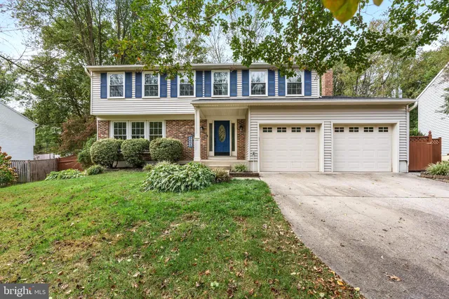 a front view of a house with a garden and trees