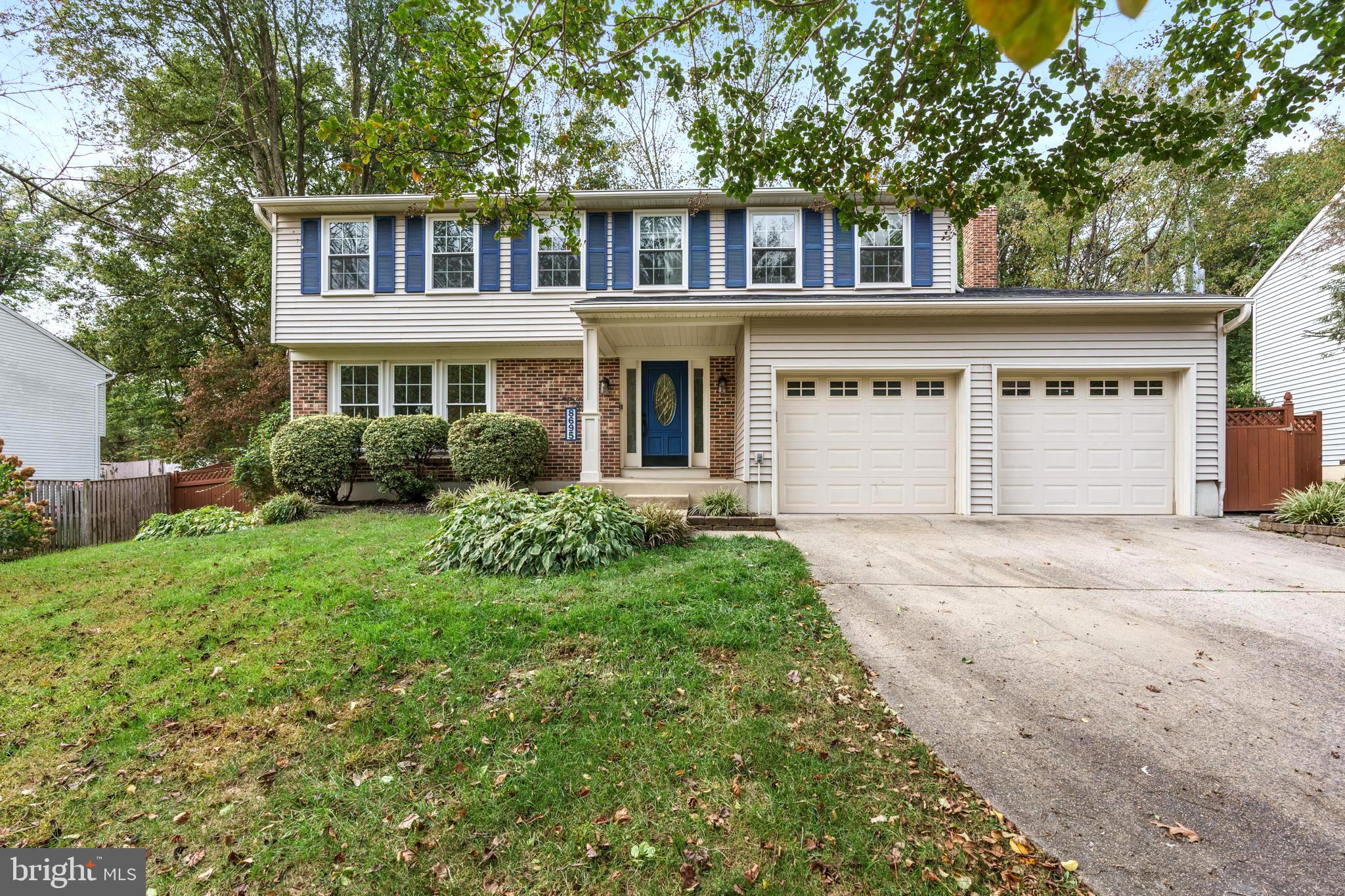 a front view of a house with a garden and trees