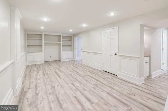 a view of an empty room with wooden floor and closet